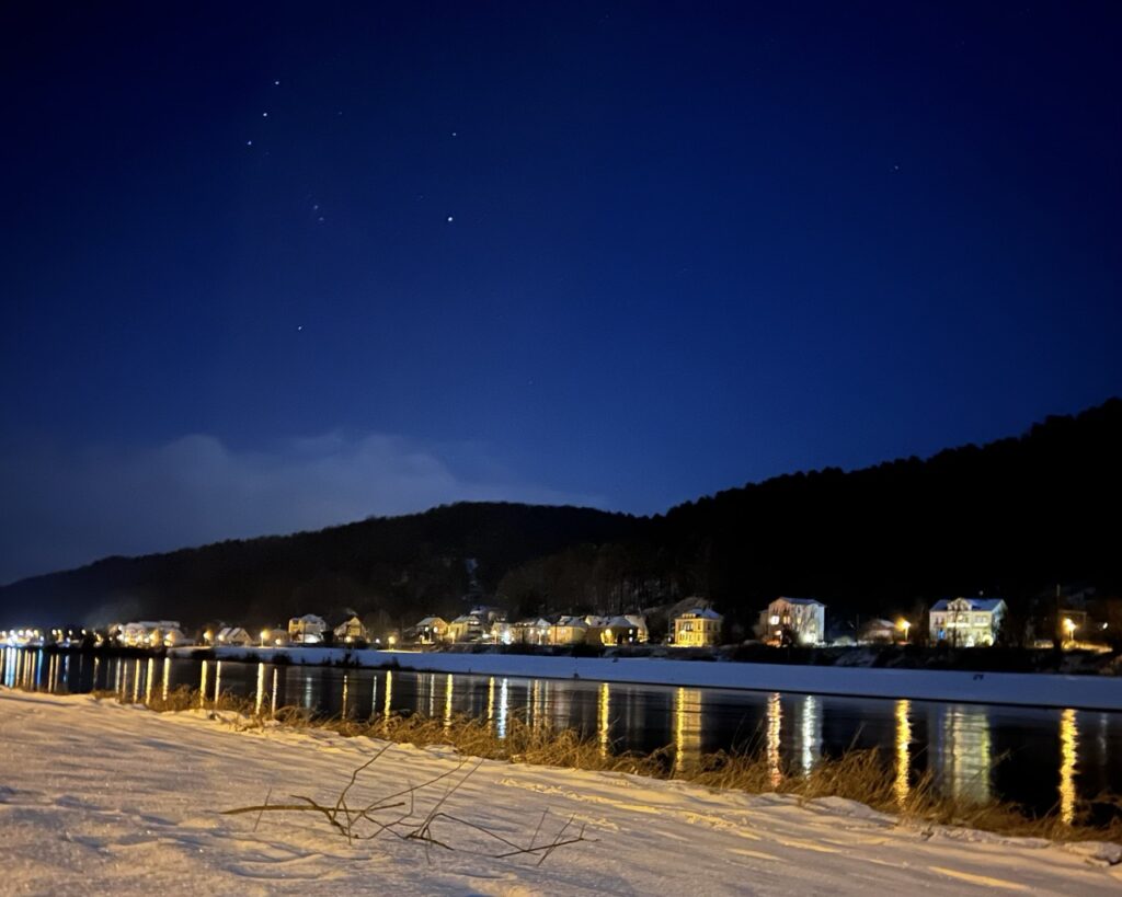 Blick auf die Elbe in der Nacht, am Elbufer liegt Schnee und am Himmel sind Sterne zu sehen